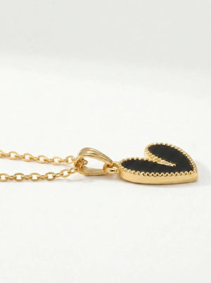 Gold necklace with a black heart-shaped pendant on a white background
