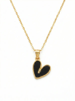 Gold necklace with a black heart pendant on a white background