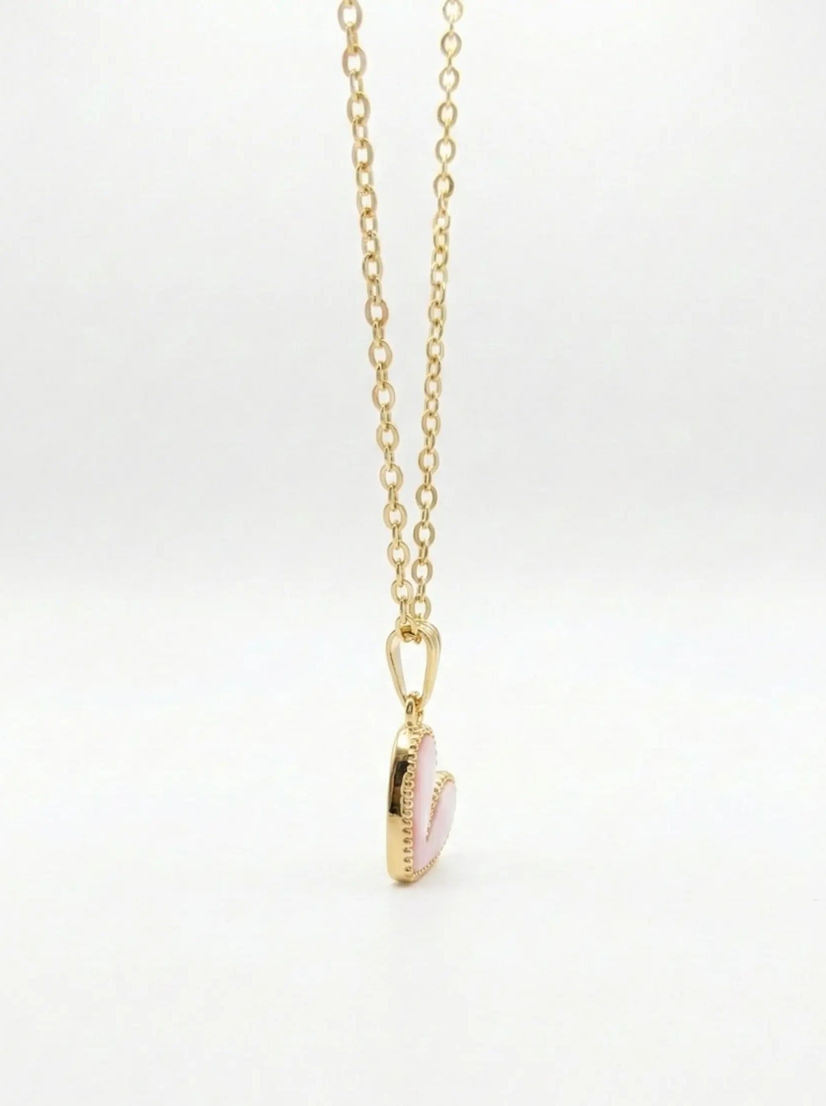 Gold necklace with a pink pendant on a white background
