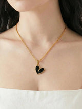 Woman wearing a gold necklace with a heart pendant on a plain background