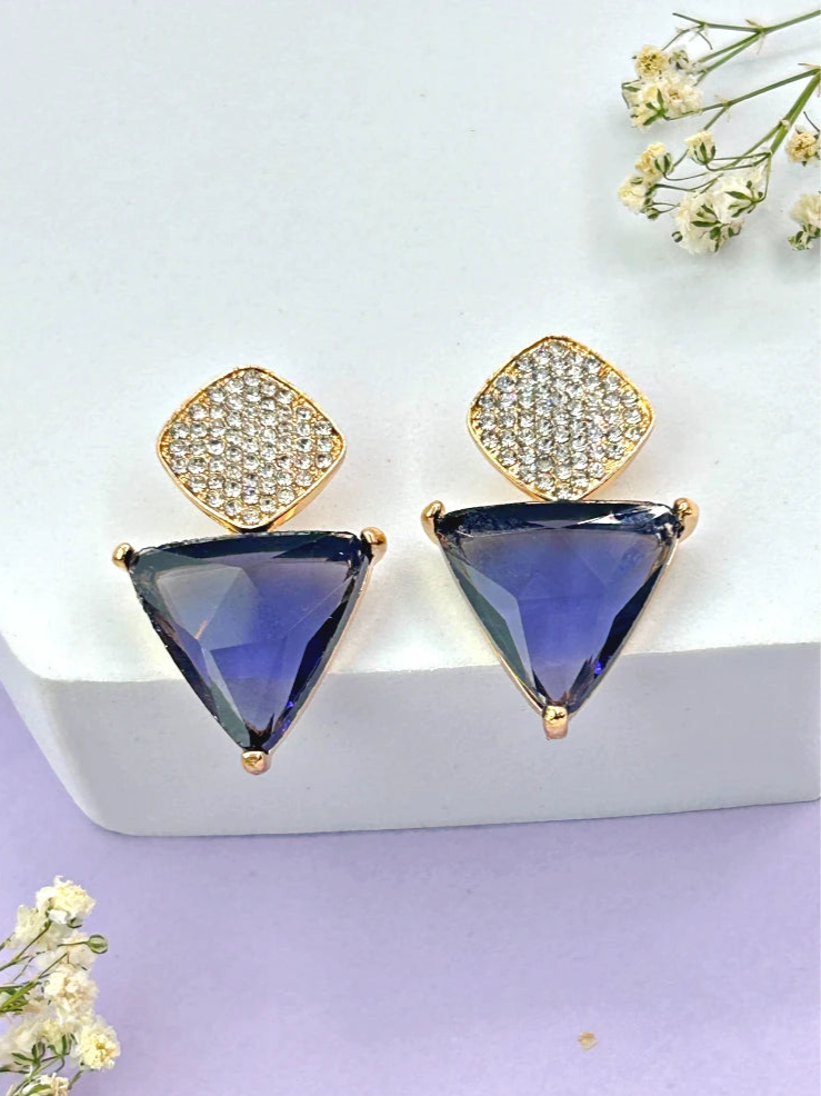 A pair of Aria purple triangle and teardrop CZ dangle earrings in a gold-tone setting on a white background